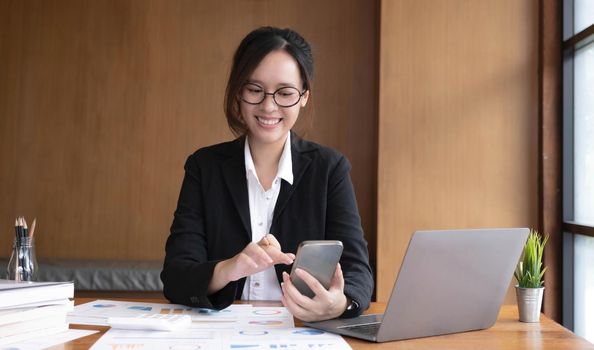 Young asian businesswoman beautiful charming smiling and using on mobile phone in the office..