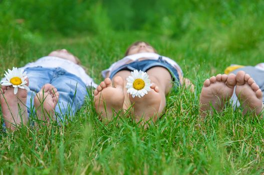 Children's feet with chamomile on green grass. Selective focus. nature.