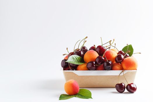 Apricots and cherries in paper packaging on a white background. the concept of eco-friendly packaging without plastic. copy space