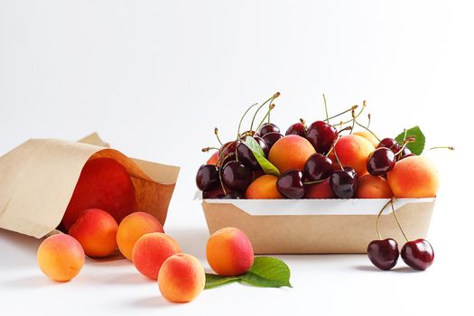Apricots and cherries in paper packaging on a white background. the concept of eco-friendly packaging without plastic. copy space