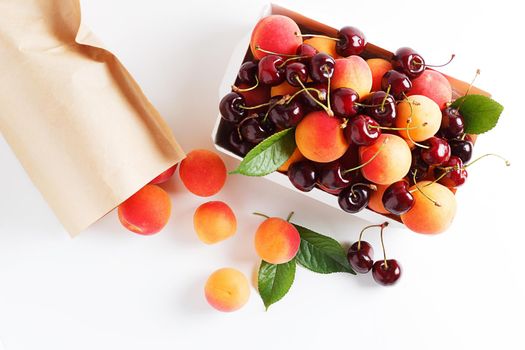 Apricots and cherries in paper packaging on a white background. the concept of eco-friendly packaging without plastic. Top view