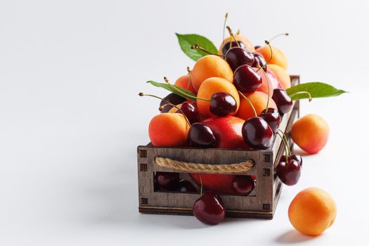 apricots and cherries in a box on a white background.Copy space