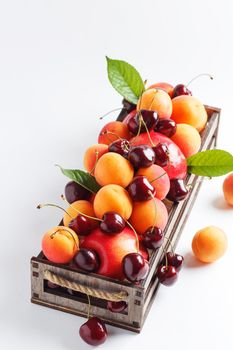 apricots and cherries in a box on a white background