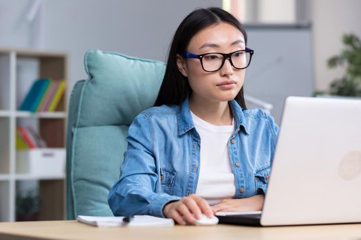 Asian freelancer woman working with laptop in home office remotely, business woman wearing casual clothes.