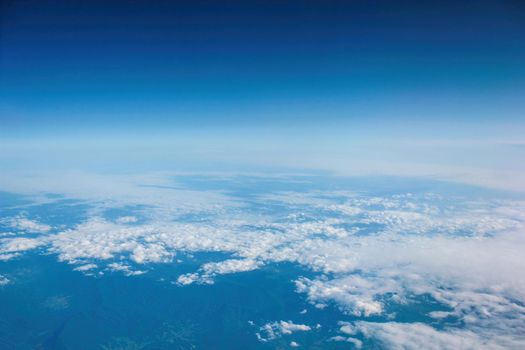 Aerial view of clouds and blue sky over ocean, cloudscape top view from airplane