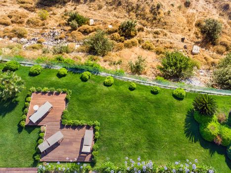 Terrace with green grass morning view. Wooden floor with chairs, looking out over the large lawn. Top view. Vacation and travel concept