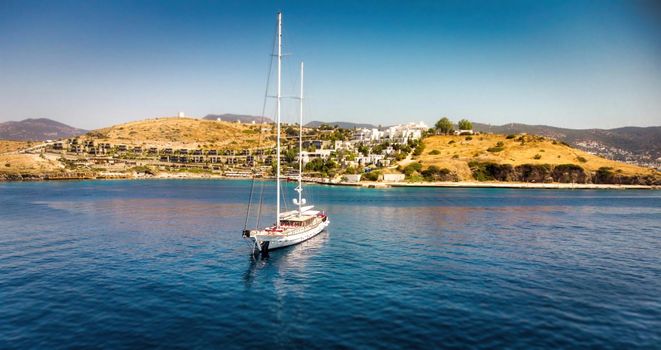 Sailing ship yachts at opened sea. Aerial drone view to sailboat. Aerial view of anchoring yacht in open water. Ocean and sea travel and transportation