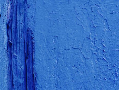 A fragment of a wall covered with blue paint damaged by time and weather.