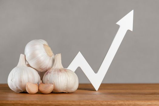 Garlic price, garlic harvest, vegetables export and import. Rising cost of vegetable crops. World food crisis. Bulbs of garlic lie on the table, the graph of the diagram points, up