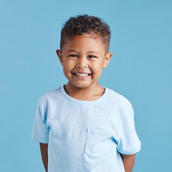 Portrait of a smiling little brown haired boy looking at the camera. Happy kid with good healthy teeth for dental on blue background.