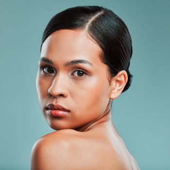 Portrait of a young beautiful mixed race woman with smooth soft skin posing against a green studio background. Attractive Hispanic female with stylish makeup posing in studio.