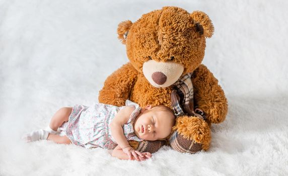 A newborn baby sleeps with a teddy bear. Selective focus.