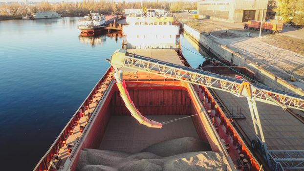 Grain loading in hold of bulk carrier ship with elevator crane closeup. export cereal