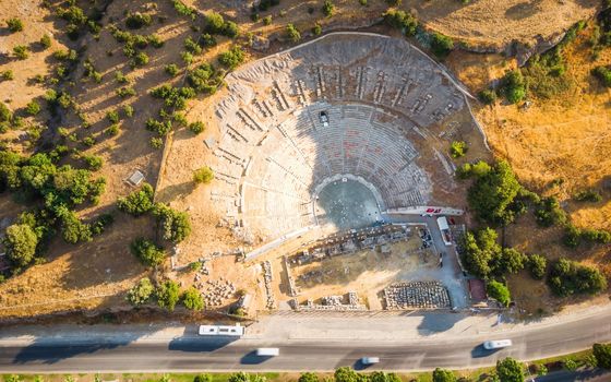 Top Aerial view of historical places, theater ruins, massive ancient theatre of Halicarnassus with highway crossing town Bodrum, Turkey. download photo