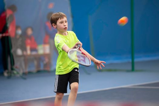 A boy with a tennis racket on the court plays tennis.