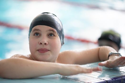 Boy in a swimming cap and swimming goggles in the pool. The child is engaged in the swimming section.