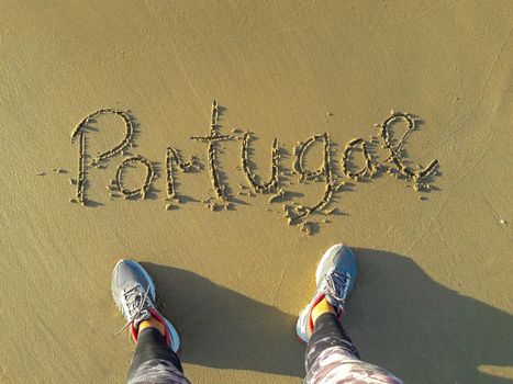 Portugal text in the sand written by hand. feet from above on a beach. download photo
