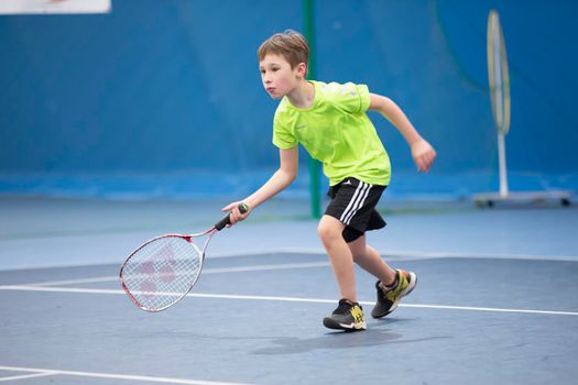 A boy with a tennis racket on the court plays tennis.