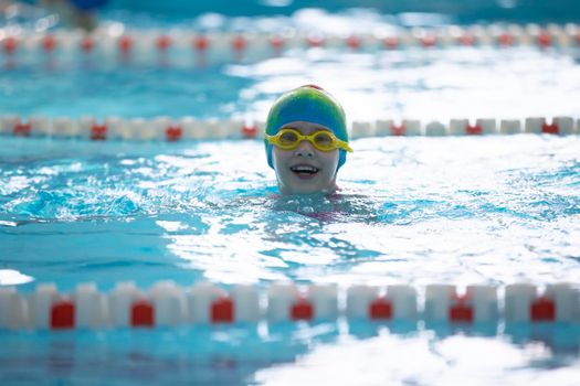 Child athlete swims in the pool. Swimming section.