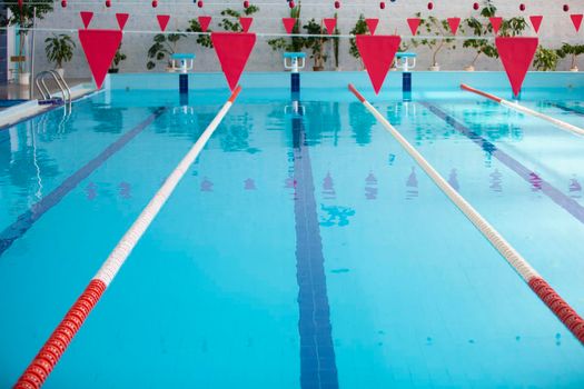 An empty sports pool with a red dividing path. Blue water in the swimming pool.