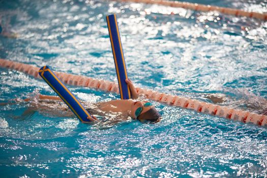 Child athlete swims in the pool. Swimming section.