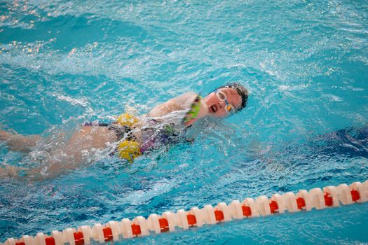 Child athlete swims in the pool. Swimming section.