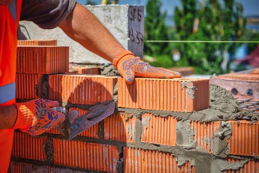 Close up of industrial bricklayer installing bricks on construction site. worker with bricks. download photo