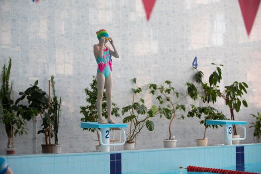 Girls in a swimsuit and a swimming cap in the sports pool.