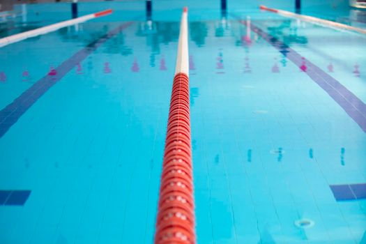 An empty sports pool with a red dividing path. Blue water in the swimming pool.