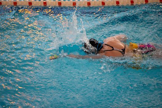 Child athlete swims in the pool. Swimming section.