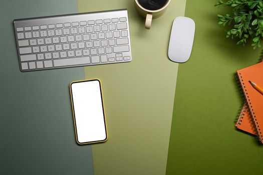Smart phone, coffee cup, notebook and houseplant on green background.