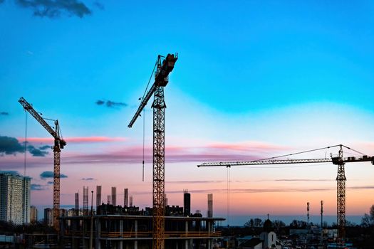 Construction site with crane. Silhouette cranes, industry concept over natural background sunset pastel. Production facility. The crane. Against the sunset. download photo