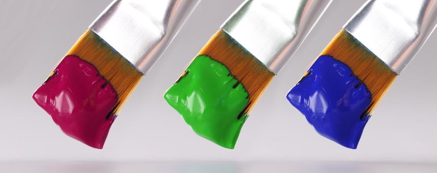 Three brushes with different paint colors. Artistic paints of different colors concept