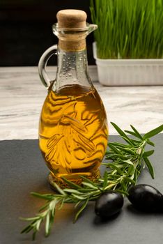 Olive oil. Olives on a background of olive oil. A bottle pours oil into a saucer close-up. Black stone table top with place for text or design.