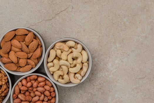Peanuts and almonds in cups on a marble table top, top view. Superfoods and healthy eating concept.
