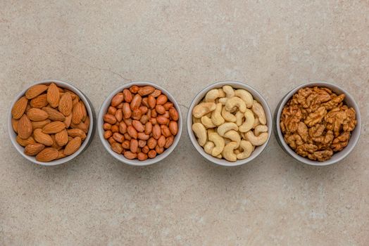 Nuts of different varieties, top view. The mixed nuts lie in bowls on a stone countertop. For design and printing. Place to insert text, recipe or entry
