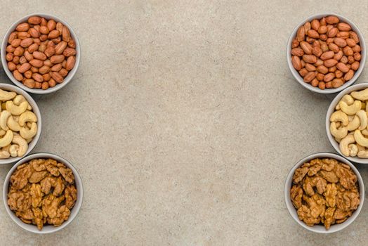 Nuts of different varieties, top view. The mixed nuts lie in bowls on a stone countertop. For design and printing. Place to insert text, recipe or entry