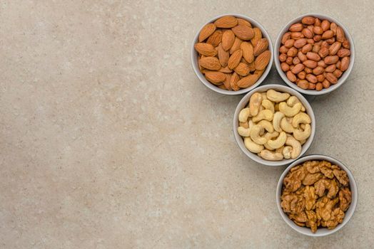 Nuts of different varieties, top view. The mixed nuts lie in bowls on a stone countertop. For design and printing. Place to insert text, recipe or entry