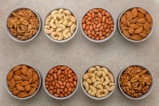 Nuts of different varieties, top view. The mixed nuts lie in bowls on a stone countertop. For design and printing. Place to insert text, recipe or entry