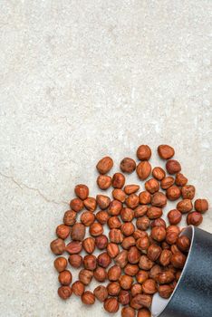 Hazelnuts on the table. A cup of hazelnuts flips over onto a marble top. Copy space.nuts in bulk lie on the table.