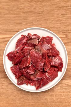 Cooking pilaf in a cauldron, a recipe for real pilaf. Ingredients for cooking pilaf on a wooden background. Raw meat on a wooden cutting board, cut into pieces.