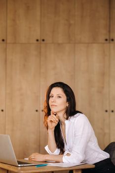 Beautiful woman sitting in the office working on a laptop.