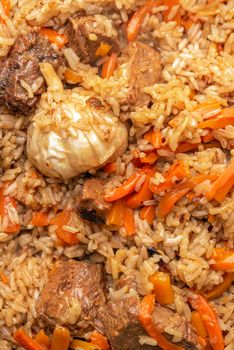 Pilaf close-up. Oriental cuisine concept. National Uzbek pilaf with meat in a cast-iron pan. Top view, lamb, devzira rice,garlic.