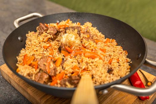 Pilaf close-up. Oriental cuisine concept. National Uzbek pilaf with meat in a cast iron pan. Top view, lamb, devzira rice,garlic.