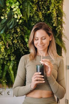 A sporty woman in sportswear holds a smoothie cocktail in her hand. The concept of healthy eating.