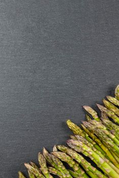 Green asparagus. Asparagus on a black slate stone background. View from above. Culinary banner with place for text. Large format for printing.