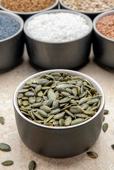 Pumpkin seeds. Peeled pumpkin seeds are in a black saucer. On a black cutting board made of stone.