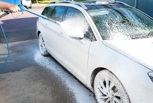 Hand washing with high pressure water in a car wash outside. A jet of foam. The concept of hand washing, self-service