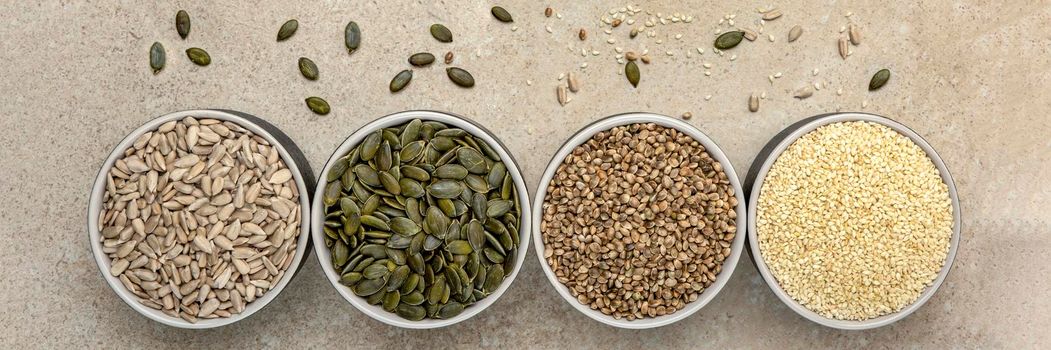 Various seeds on a marble background. Assortment, seeds set, healthy food ingredients, superfoods, copy space. Sunflower, flax, pumpkin, cannabis poppy seeds