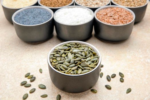 Pumpkin seeds. Peeled pumpkin seeds are in a black saucer. On a black cutting board made of stone.